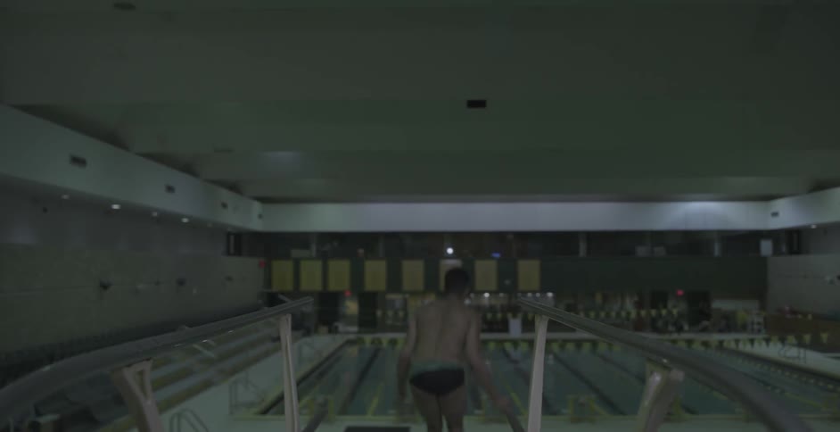 A male diver twists and turns as he dives into a pool