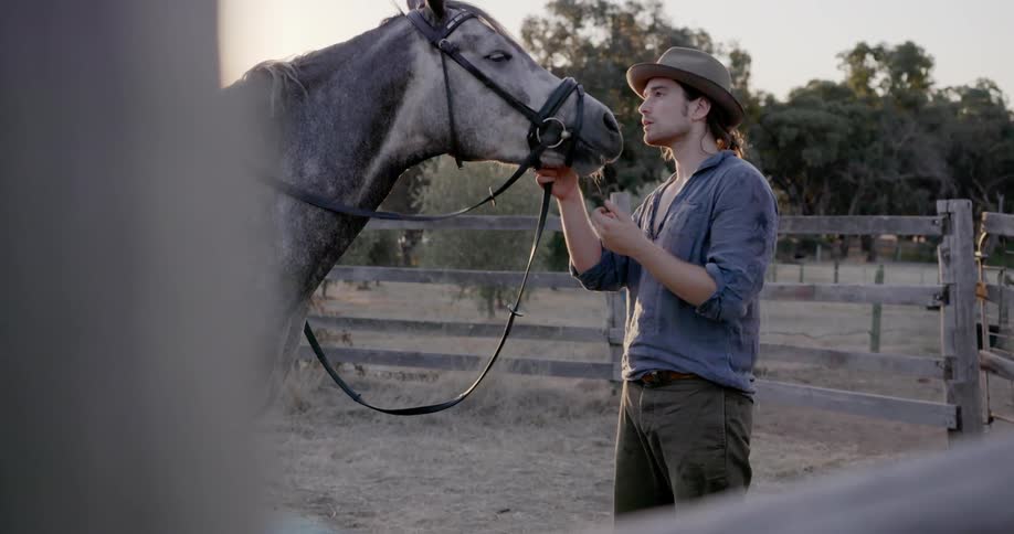 A man pets his horse behind the fence