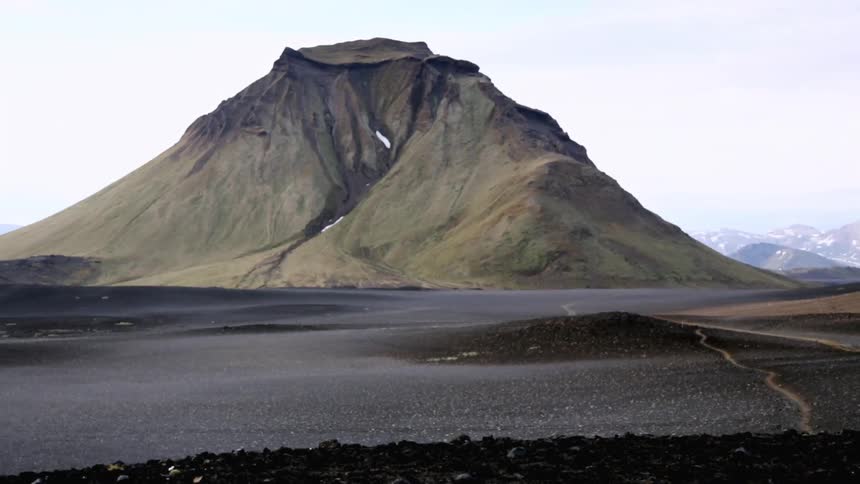 A mountain surrounded by dark gravel