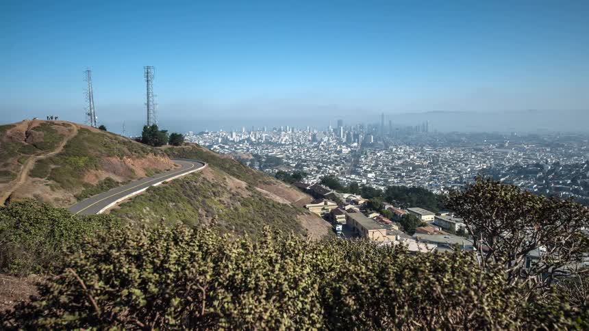 People climb a trail to the top of a hill overlooking the city