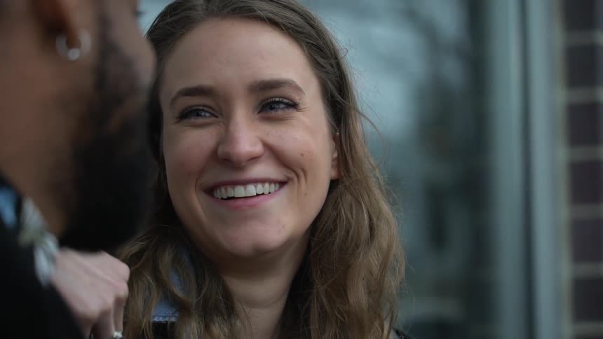 A woman and man are smiling and laughing as the sit talking outside