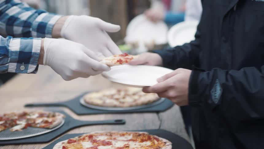A chef serves pizza slices to a person
