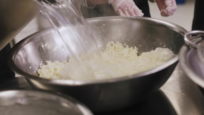 People in a kitchen mix water in a bowl