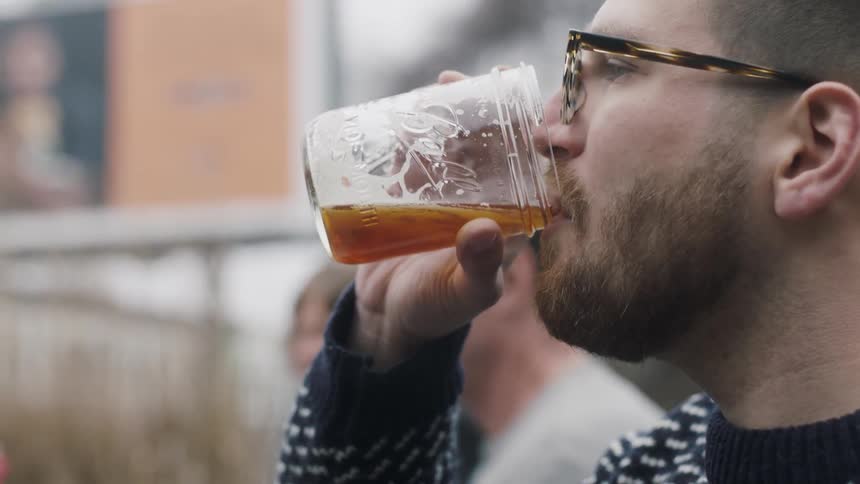 A man is drinking from a glass outdoors