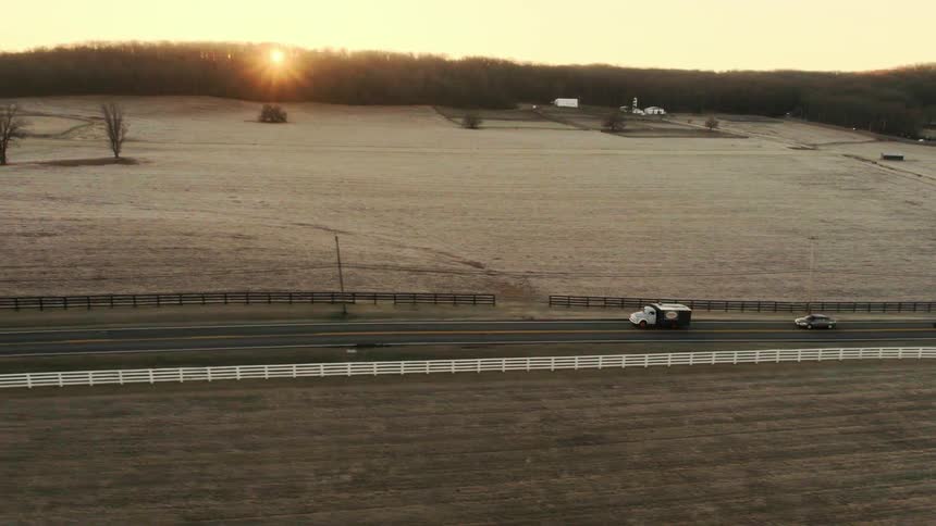 Vehicles travel down a country road on a winter morning