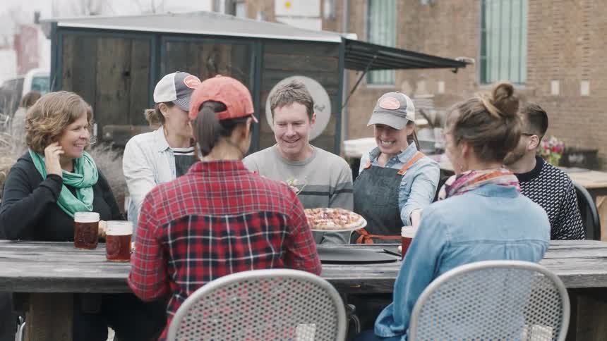 People sit down as they are served pizza