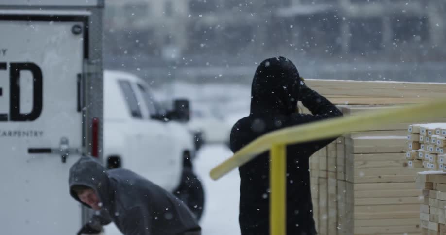 People grab boards of wood as it snows