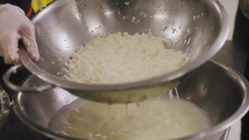 A man uses a strainer above above a bowl