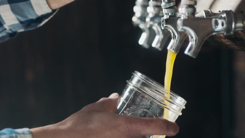 A man pours liquid into a mason jar