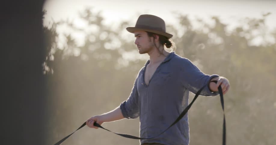 A man wearing a hat leads a horse in a circle