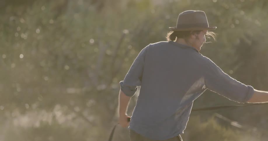 A man snaps a lead as he trains a horse in the sunshine