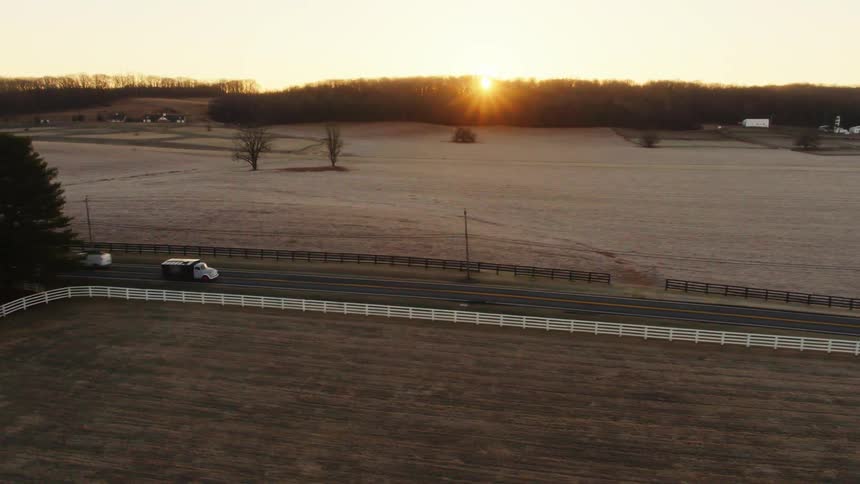 Vehicles travel along the road at sunset
