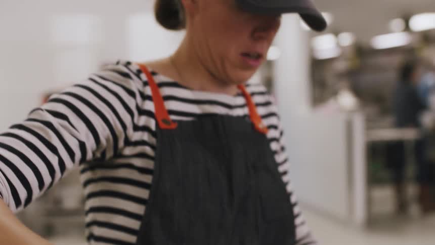 Woman lifts dough from a silver container