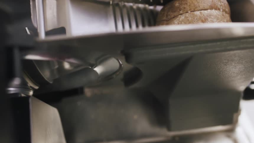 A person is cutting meat in a deli