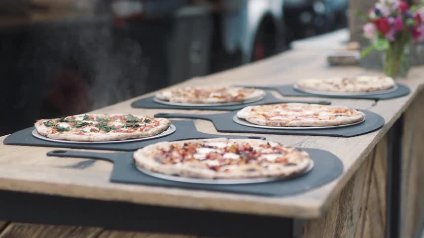 Thin crust pizzas on a wooden table top