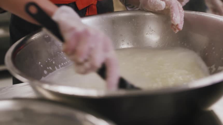 A woman is mixing ingredients in a large bowl