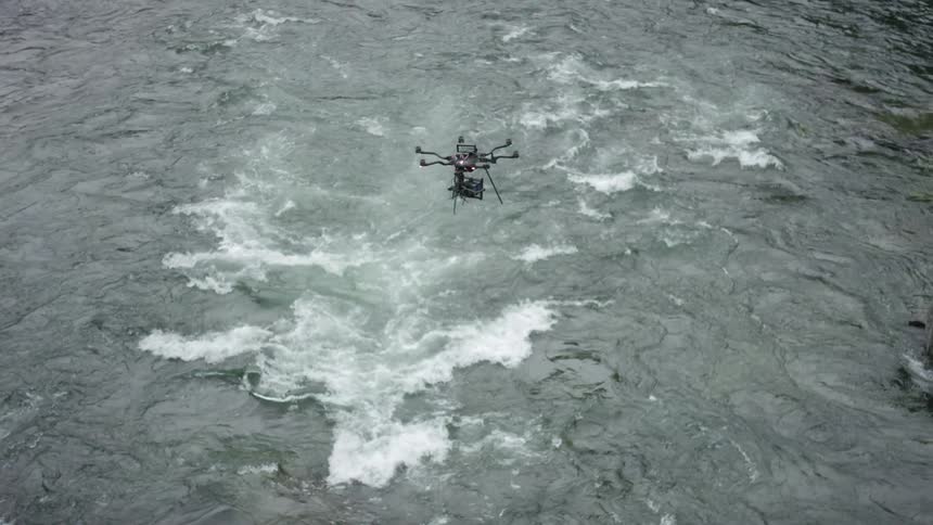 A drone flies over a choppy river