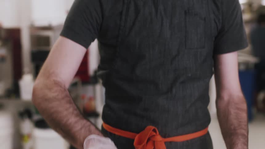 A chef stirs a mixture in a large steel bowl