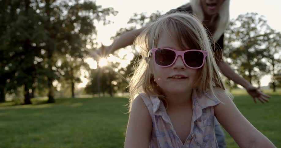 A woman walks past a girl wearing sunglasses