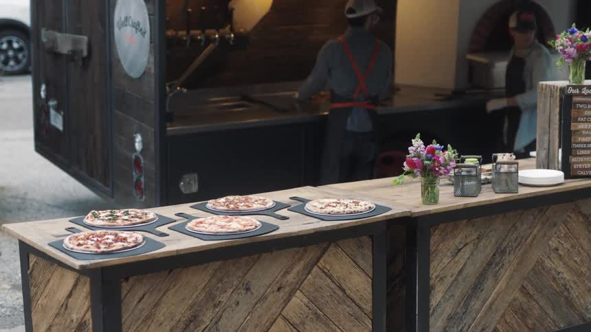 A line of thin crust pizzas on a wooden counter
