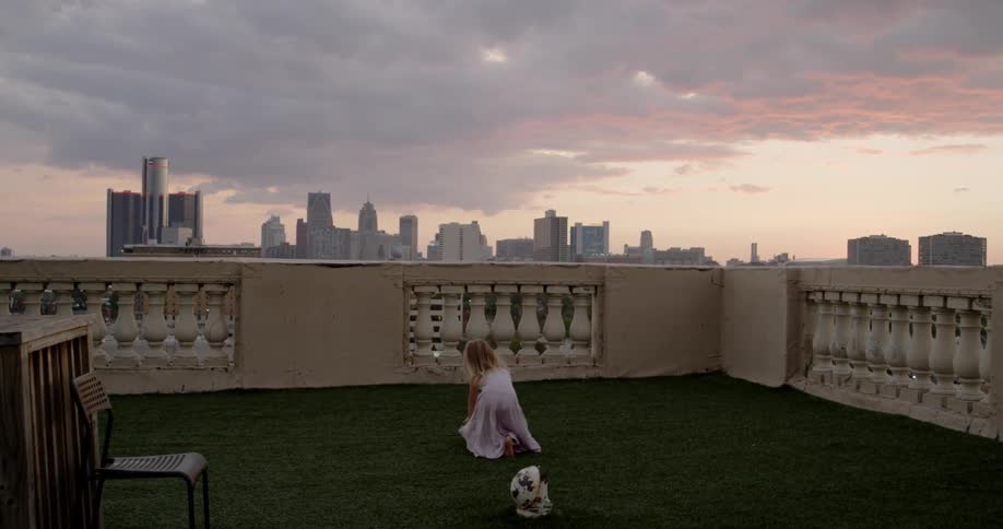 A girl runs on the roof near the city