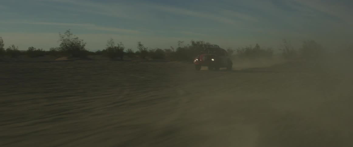 A rally car drives through the desert
