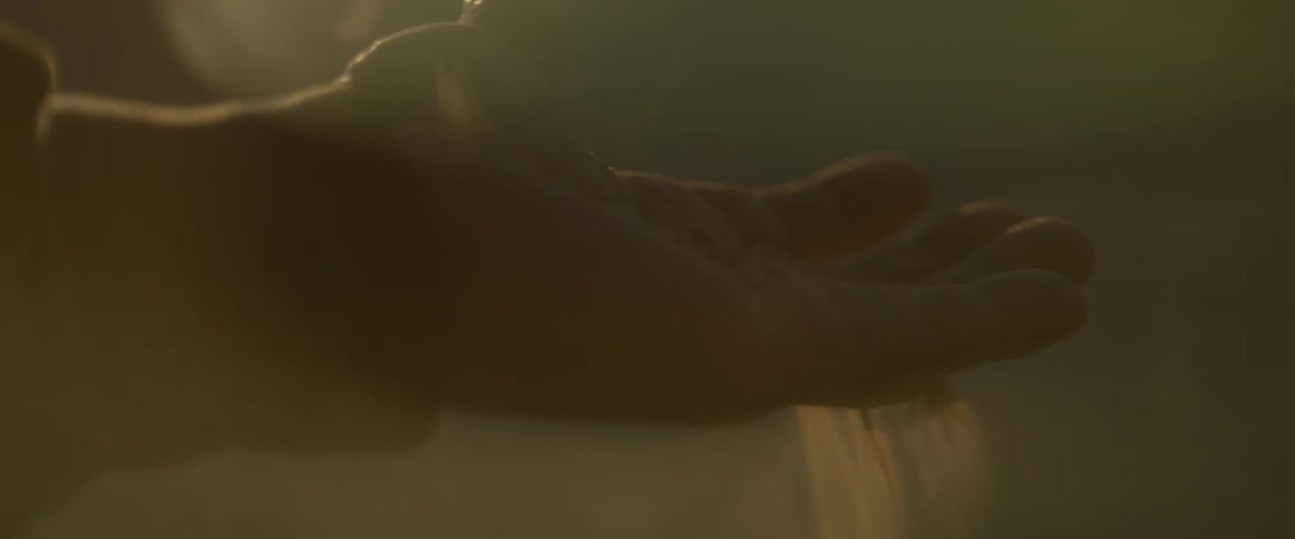 Sand falls through a mans fingers