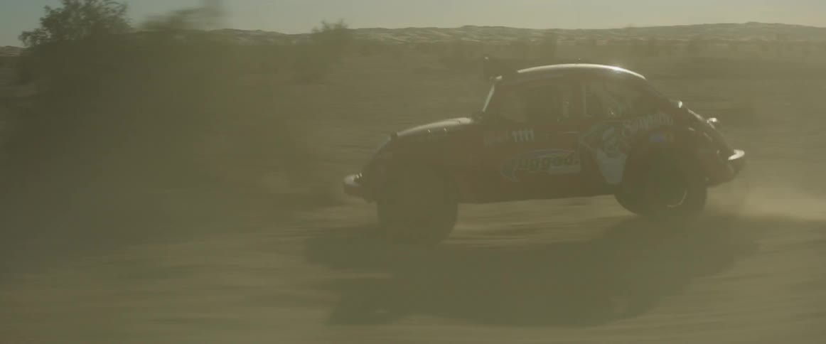 A vehicle races in the desert jumping all over
