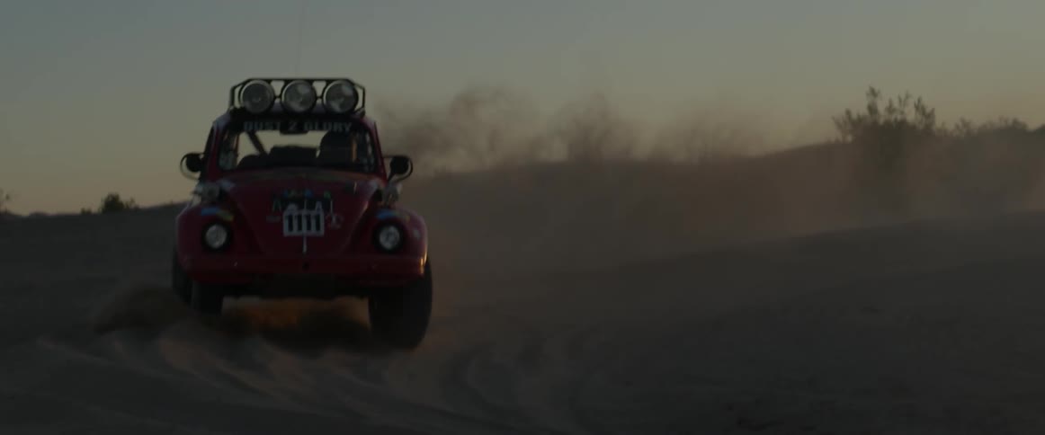 A man drives a rally car through the desert
