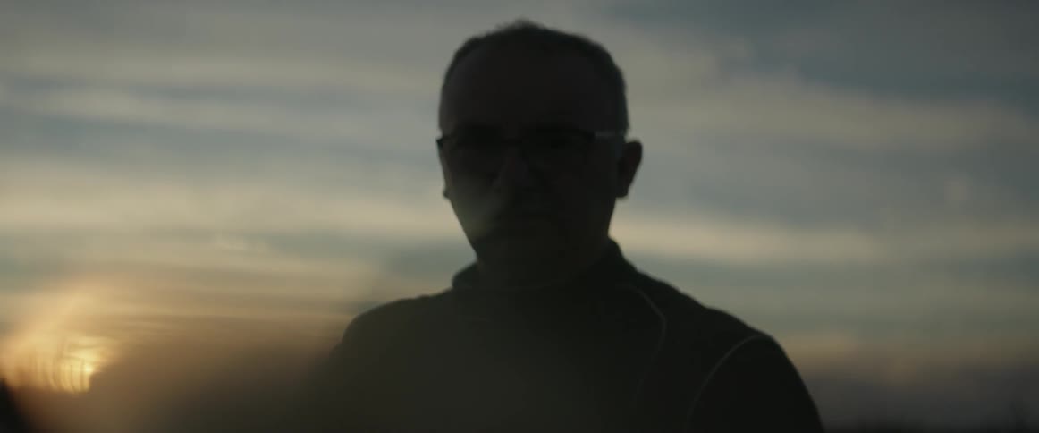Man wearing glasses exhales smoke out through his nostril
