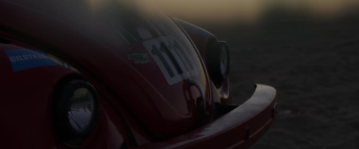 The car is parked in the desert at dawn