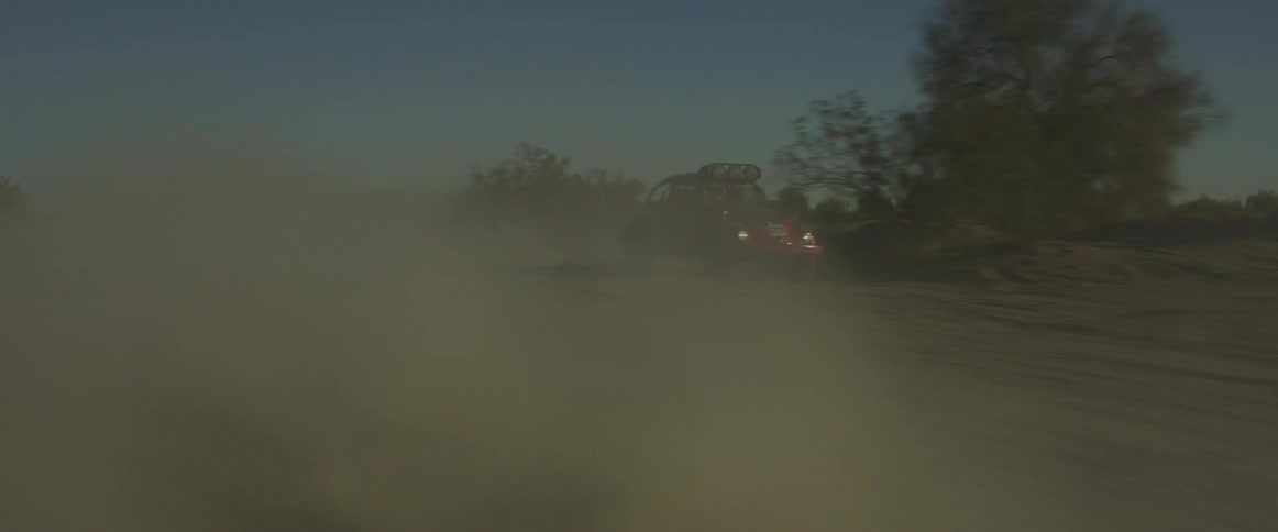 A rally car drives through the desert