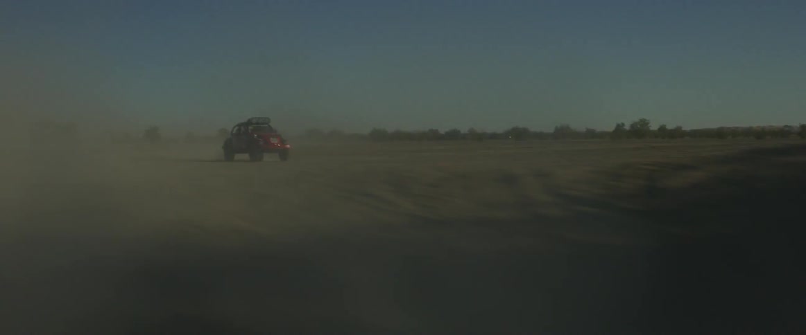 A rally car drives through the desert