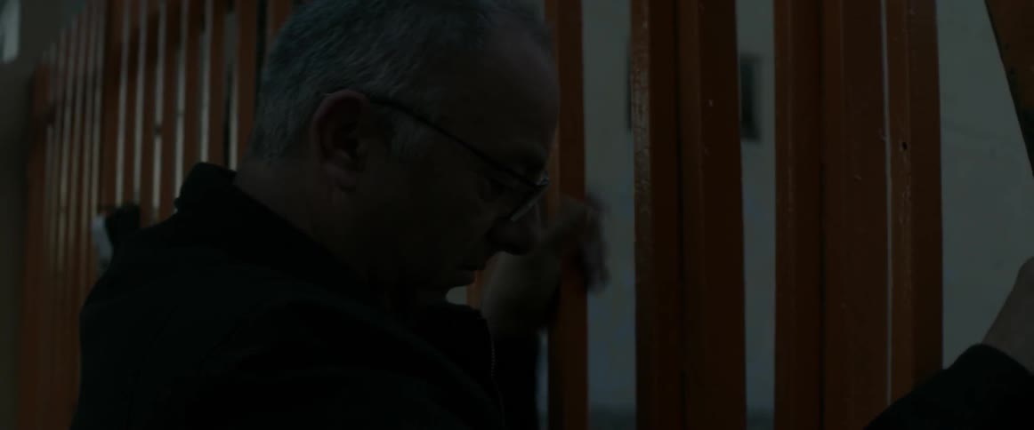 A man walks past a building to open a fence