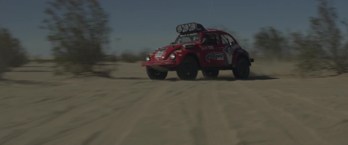 A rally car drives through the desert