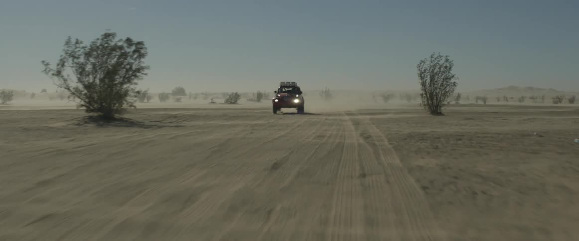 A man drives a rally car through the desert