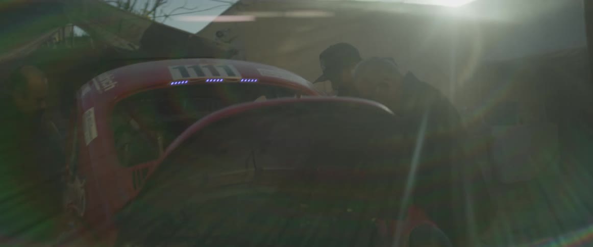 Three people are working on a car in the yard
