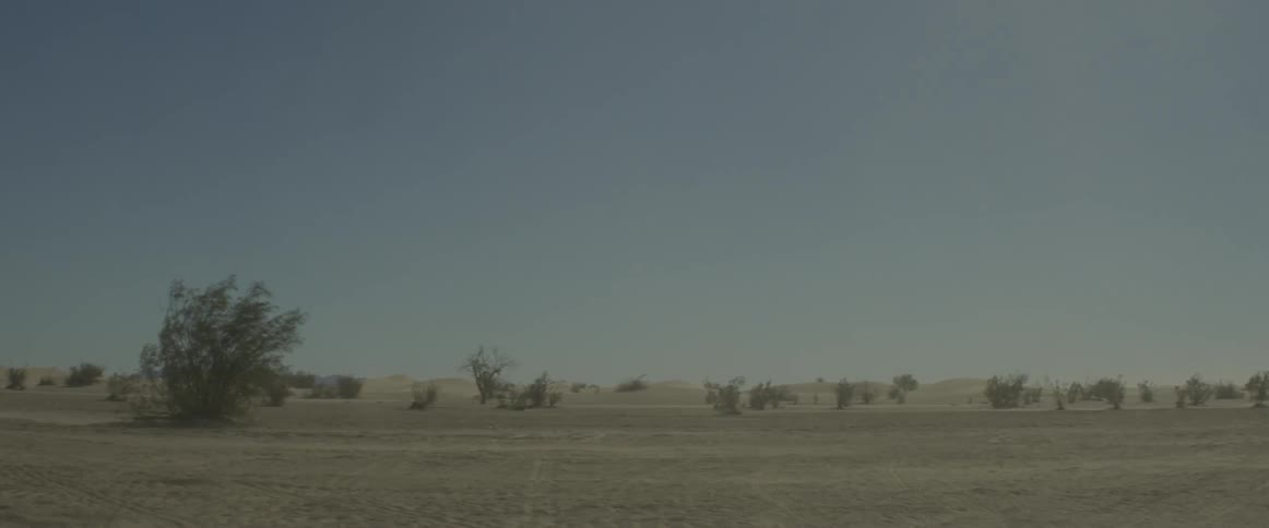 A motorcycle kicks up dust as it drives by on a rural road