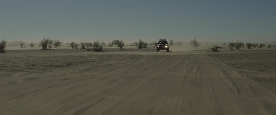 A car races in the desert making turns