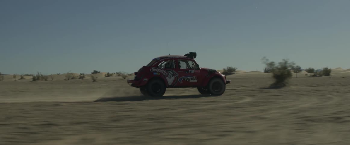 A car is driving off road in the desert