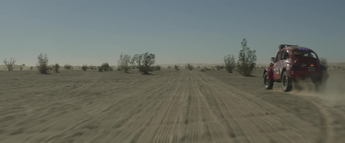 A car is off roading in the desert and kicking up dust