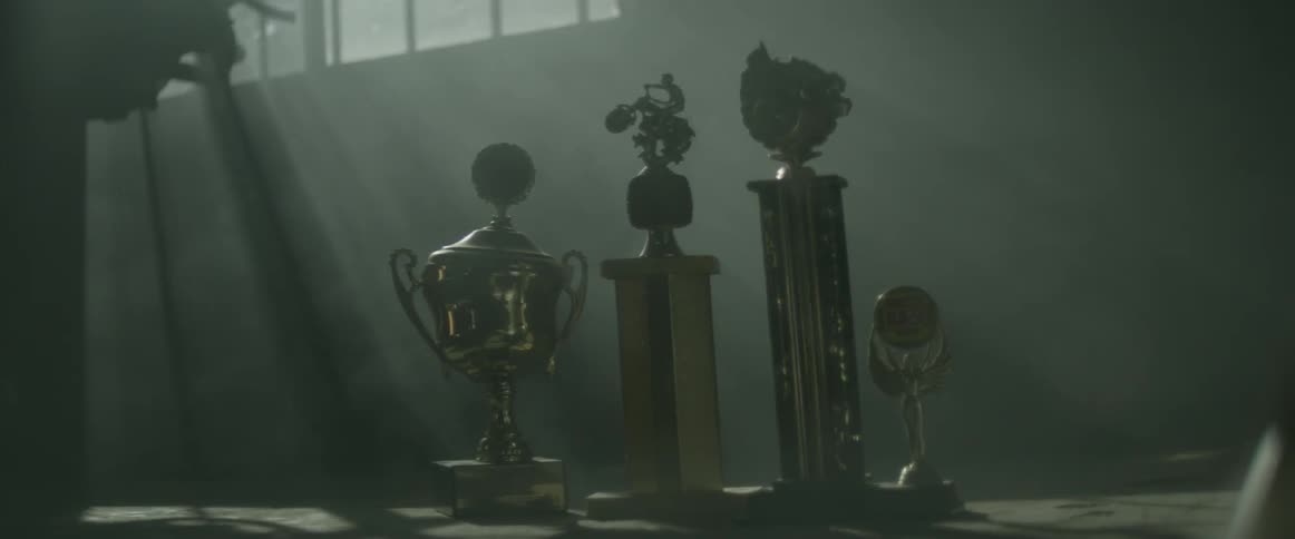 The table is covered with sports trophies