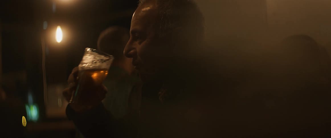 A man drinks beer in a dark bar