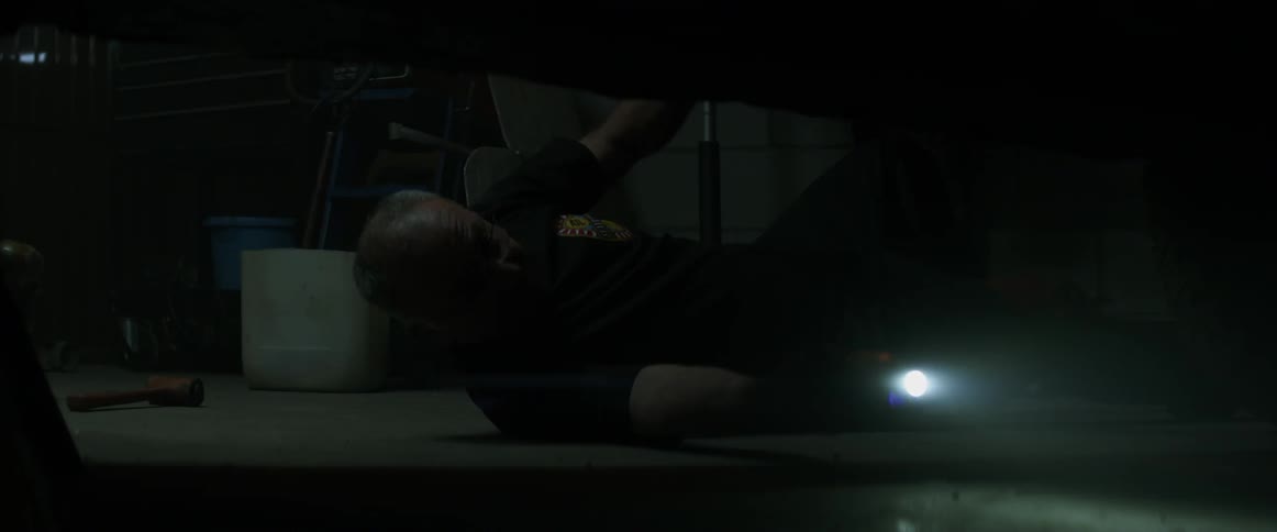 A man gets on the ground to work under a car