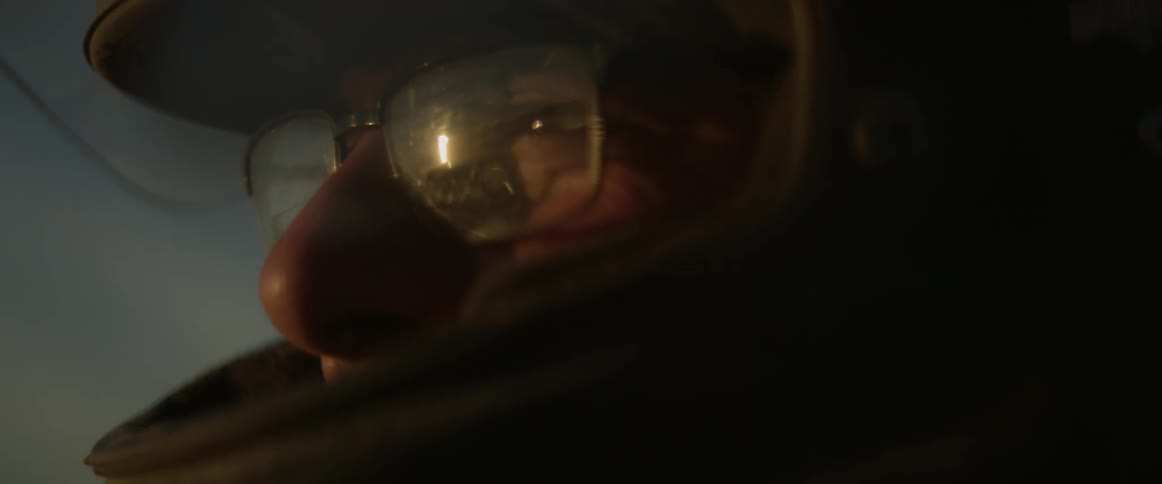 A man wearing a rally racing helmet looks towards the sun