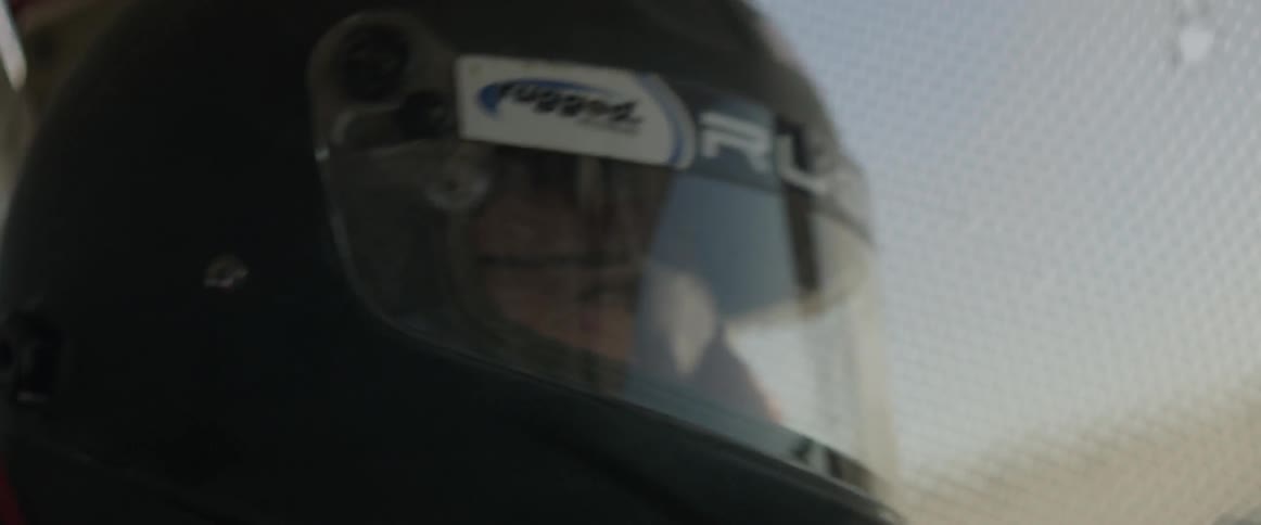 A man wearing a racing helmet navigates at high speed