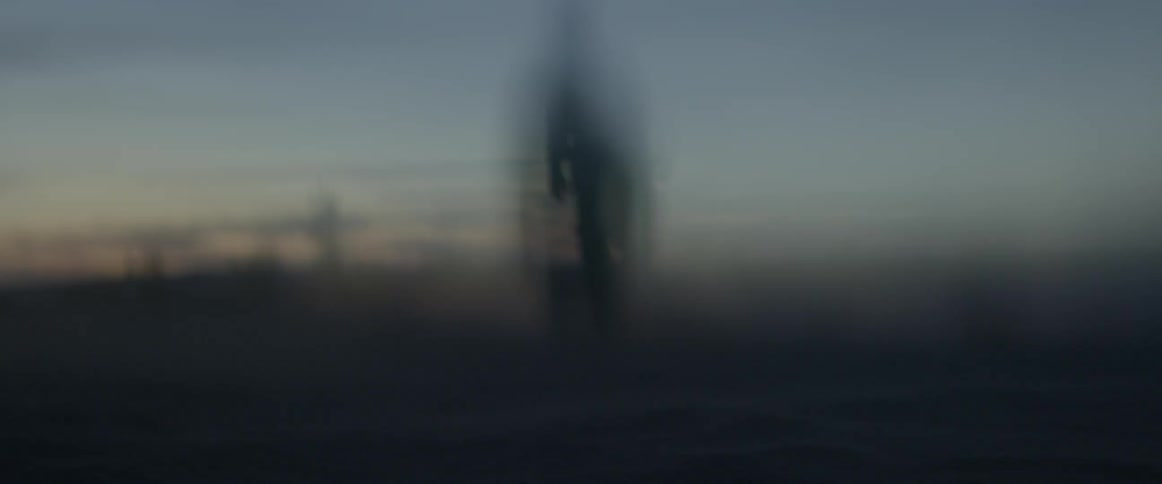 A man walks outside at dusk