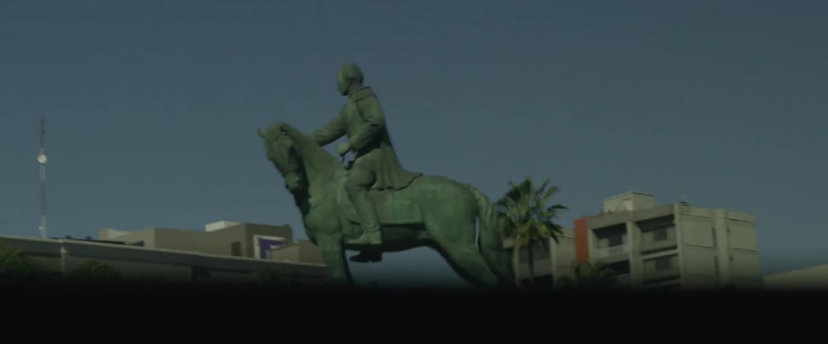 A statue of a man on a horse can be seen from the city highway