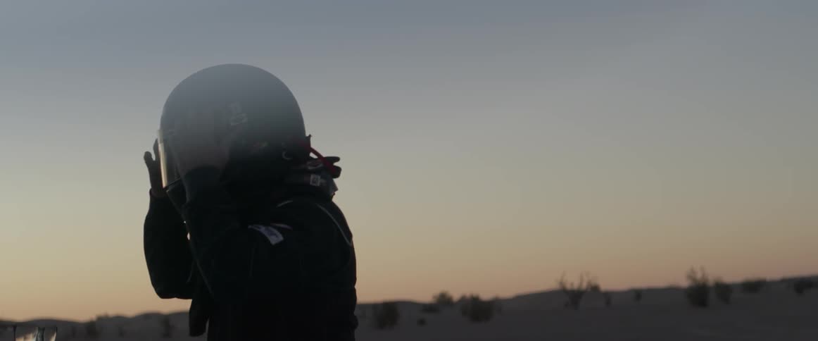 A man puts on a helmet in the desert