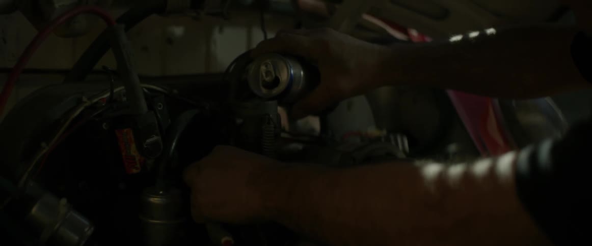 A man is working on a vehicle engine in the dark